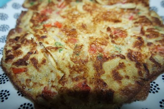 Close-up view with selective focus of egg omelet with peppers and spices sprinkled