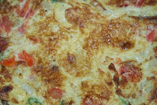 Close-up view with selective focus of egg omelet with peppers and spices sprinkled