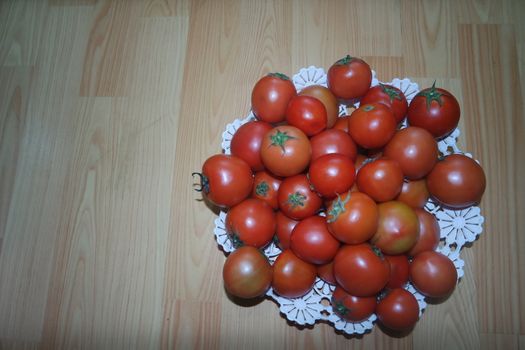 Close-up view of red tomatoes in white basket on a wooden floor in market for sale. A fruit background for text and advertisements