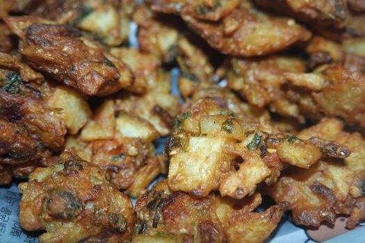 close-up view with selective focus of crispy basin pakora/pakoda or patties are popular indian or pakistani street food snack, served with green salad and sauce. Selective focus of