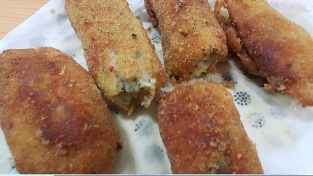 Closeup perspective view of home made spicy and delicious croquettes served in ceramic plate over wooden floor