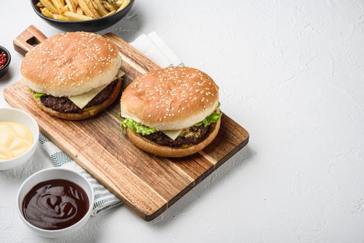 Set of beef burger and french fries on white textured background with space for text.