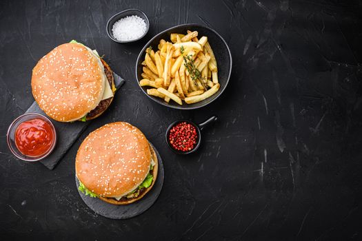 Craft beef burger and french fries on black background, flat lay with copy space.
