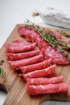 Salchichon whole and sliced cuts, spanish sausage on white textured background.