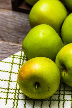 Detail on ripe green apples on wooden table.