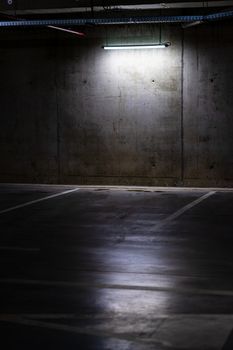 Empty parking lot with overhead dim light, underground parking garage.