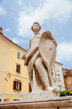 Ancient statue in 1st of May Square on a hot summer's day in Piran, Slovenia