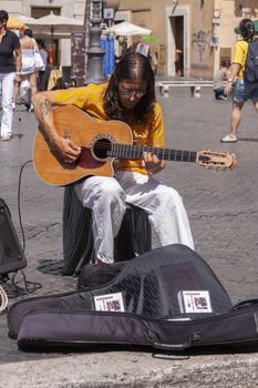 Rome, Italy - June 28, 2010: A busker man, works and begs for alms, playing the guitar in Piazza Navona, Rome.