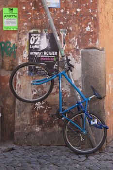 Rome, Italy - June 28, 2010: A blue mountain bike, hanging in a corner of one of the central streets of Rome.