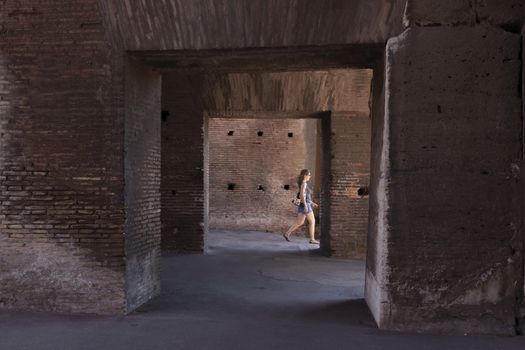 Rome, Italy - June 29, 2010: A tourist woman walks, looking for the exit, between the corridors, arches and passageways inside the Colosseum, Rome.