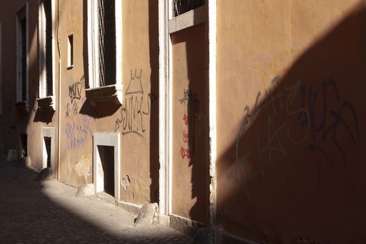 Rome, Italy - June 29, 2010: The evening light falls glancingly on one of the salmon-colored walls of a street in Rome.