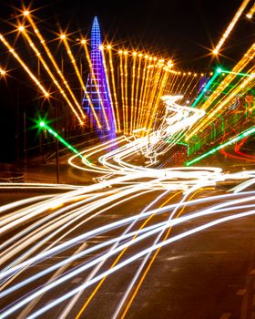 Traces of headlights from cars moving at night on the bridge, illuminated by lanterns. Abstract city landscape with highway at dusk. 