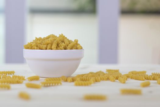 Fusilli in white cups placed on a wooden table.