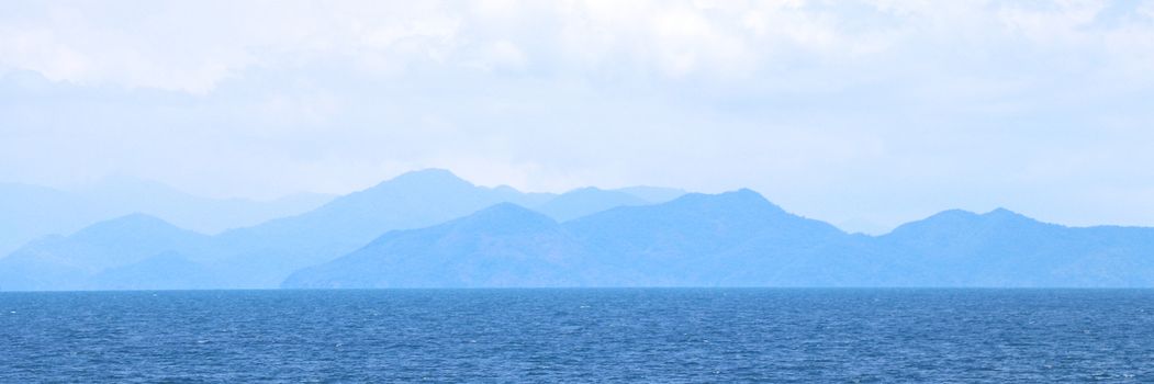 Blue sea with mountains and sky banner background.