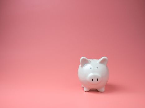 white piggy Bank on pink background with copyspace for design.