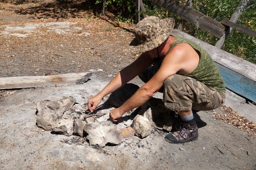 a man lighting a fire on a camping trip.