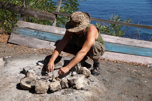 a man lighting a fire on a camping trip.