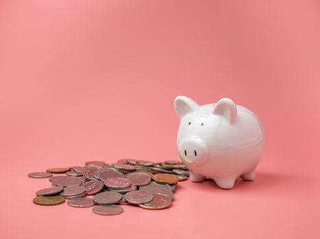 White piggy bank and coin On a pink background with copy space for design.