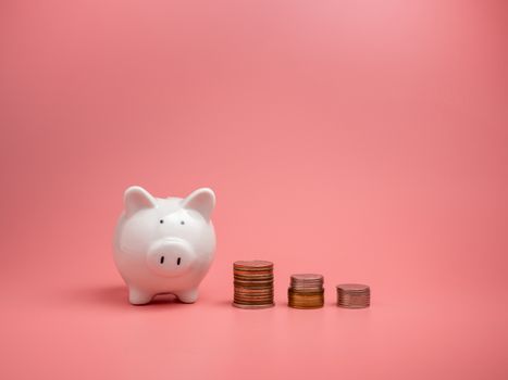 White piggy bank and coin On a pink background with copy space for design.