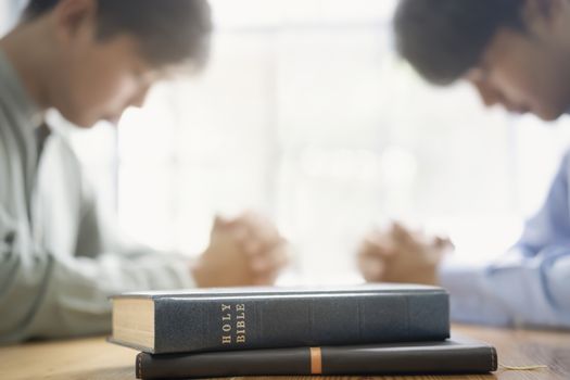 Two christian people are praying together over holy bible.