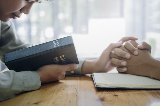 Two christian people are praying together over holy bible.