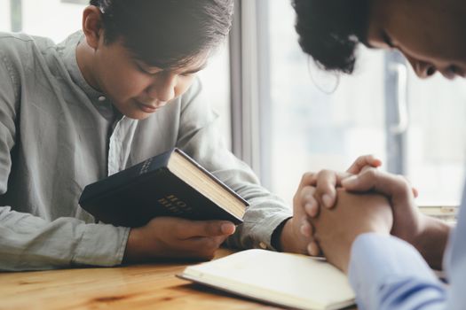 Two christian people are praying together over holy bible.