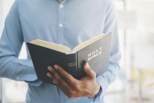 Religion Christianity concept. Man holding and reading the holy Christian Bible.