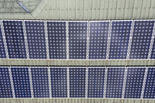 Blue solar panels on a green tiled roof in the bright sunshine.