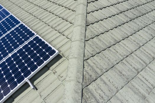 Blue solar panels on a green tiled roof in the bright sunshine