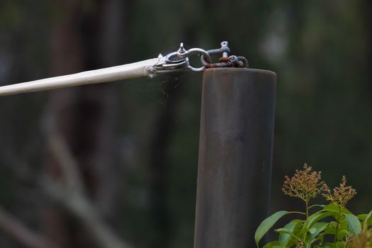 A stainless steel turnbuckle shackle connected to a black metal pole holding up a shadecloth