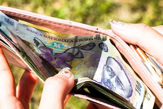 Hands holding and showing wallet with romanian money LEI.