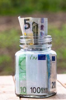 Composition with saving money banknotes in a glass jar. Concept of investing and keeping money, close up isolated.