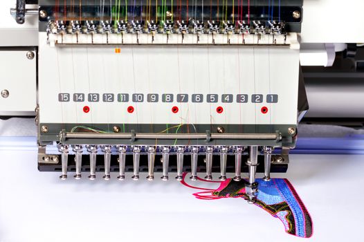 Modern professional embroidery machine for embroidery on various fabrics with multicolored threads, selective focus, place for text.