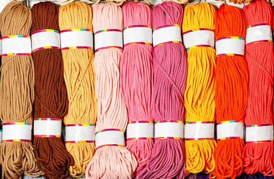 Skeins of polyester cord in various bright colors of hot shades, rolled into rolls, close-up, copy space.