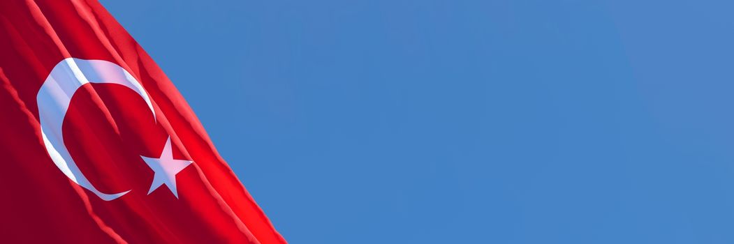 3D rendering of the national flag of Turkey waving in the wind against a blue sky