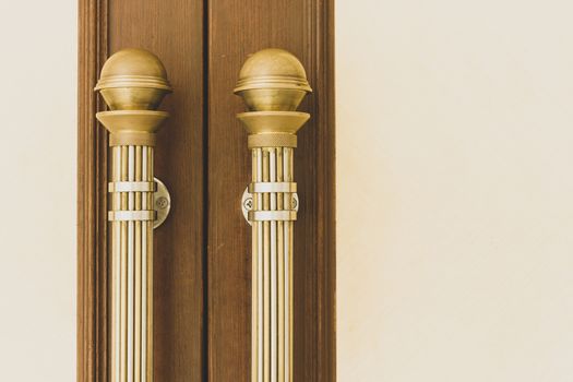 Vintage gold door handle front side of entrance interior home. Close-up closed light wooden doors in style in the interior. Doorways fittings for hotel indoor design. House apartment entryway