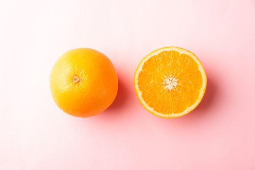 Top view of Fresh half orange fruit slice and full orange in the studio shot isolated on pink background, Healthy food concept