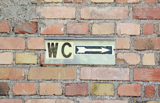 Toilet sign on an old brick wall, go right
