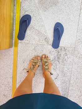 Woman wants to swap new blue flip-flops for old cream sandals.