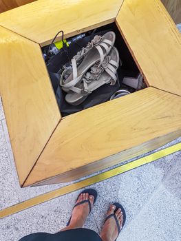 Woman throws her old flip-flops sandals into a garbage can.
