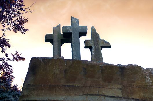 Three christian crosses on the edge of a mountain. Three crosses in silhouette on a hill with sunset. Easter or halloween background