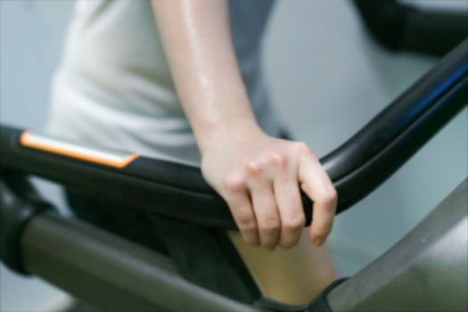 blur photo of water bottle and tired woman jogger hand on treadmill