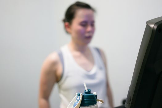 water bottle on blur background of tired woman jogger on treadmill