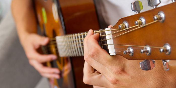 Young boy playing guitar. Close-up of man hand playing classic guitar. teenager learning playing guitar,Banner or panoramic shot.