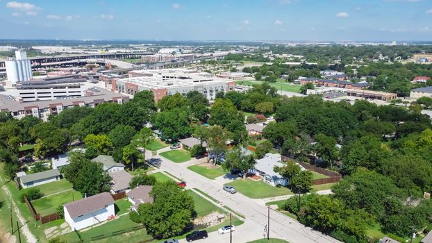 Aerial view residential neighborhood with detached family houses next to apartment buildings near historic downtown Carrollton Square, Texas. Elevated highway and light rail road in background