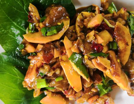 Santol spicy salad mixed with Nam Poo Chili Paste thai style on white plate