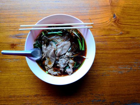 Beef noodles in herbal broth, placed on a wooden table