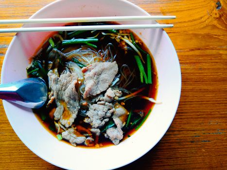 Beef noodles in herbal broth, placed on a wooden table