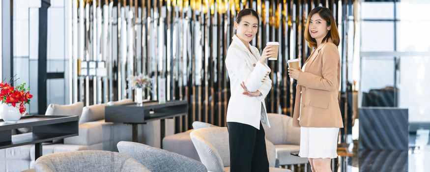 Banner, web page or cover template of Two asian businesswomen talking during coffee break in modern office or coworking space, coffee break,relaxing and talking,business and people partnership concept