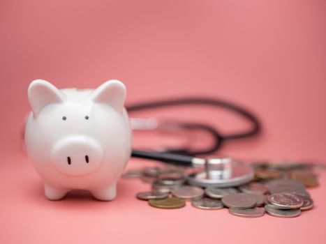 Stethoscope on the pile of money and piggy bank on pink background.
Financial health check concept, debt and finance crisis.